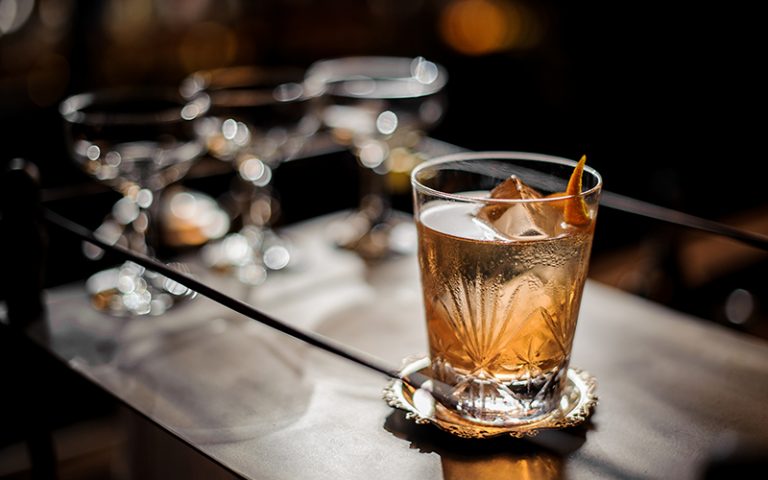 Fresh old fashioned summer cocktail with ice and orange peel
